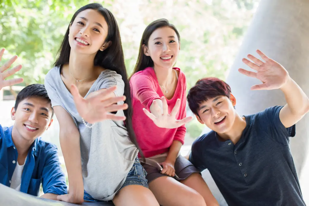 Singaporean teens waving to the camera and smiling