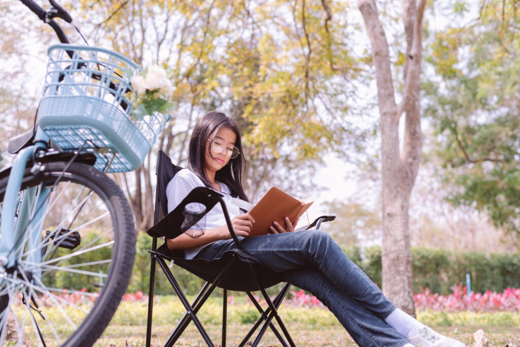 Secondary 3 student reading outdoors to build critical thinking and English skills.
