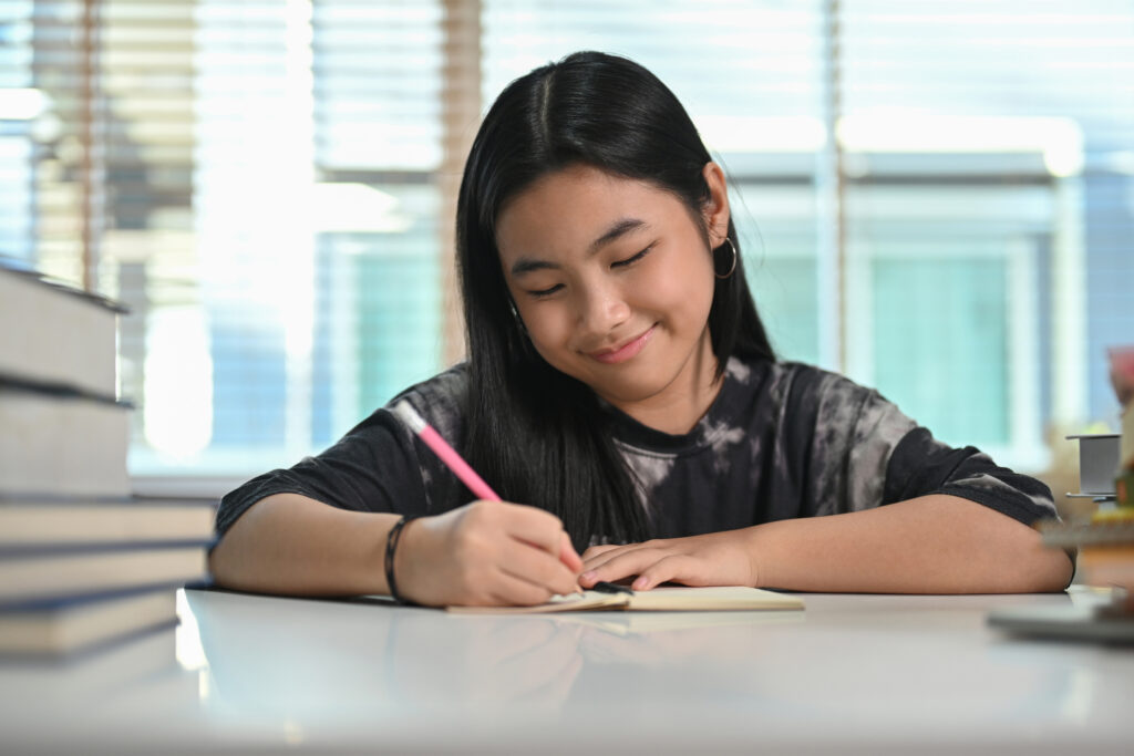 Secondary school student writing in a notebook at a study desk, illustrating essay planning, writing skills, and independent learning for secondary English.